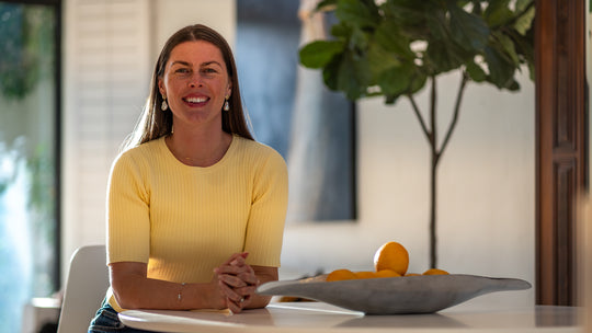 A smiling real estate agent, Abby Miller, sitting at a table with a property for sale in the background.