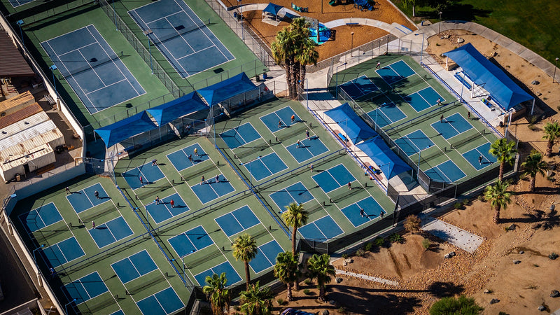 Daytime aerial of players on the blue and green pickleball courts at Fritz Burns Park in La Quinta.