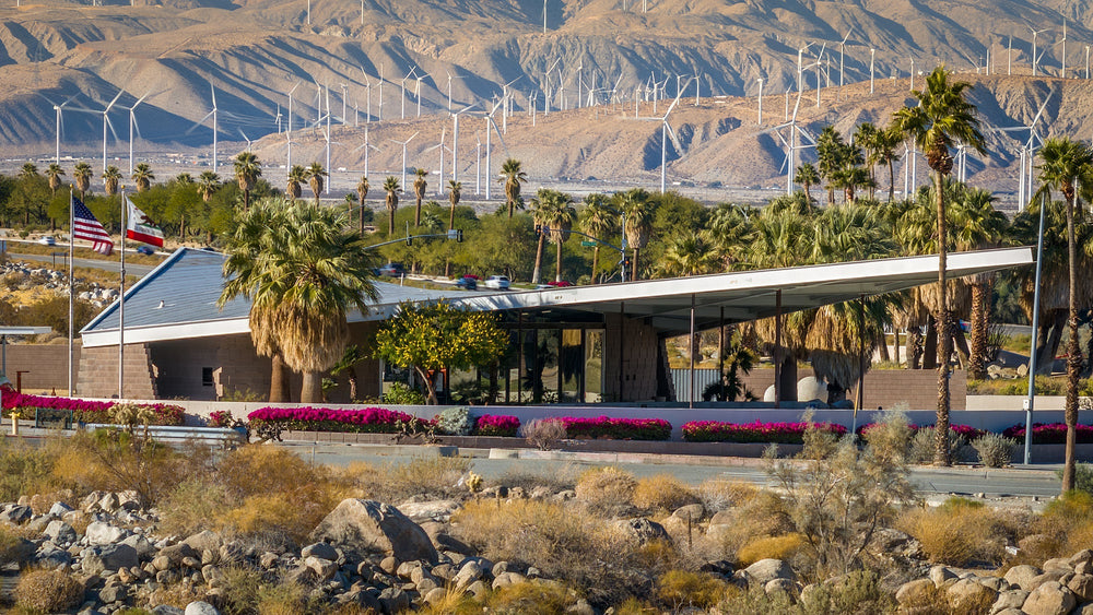 Palm Springs Visitor Center with palms, wind turbines, and desert mountains behind it