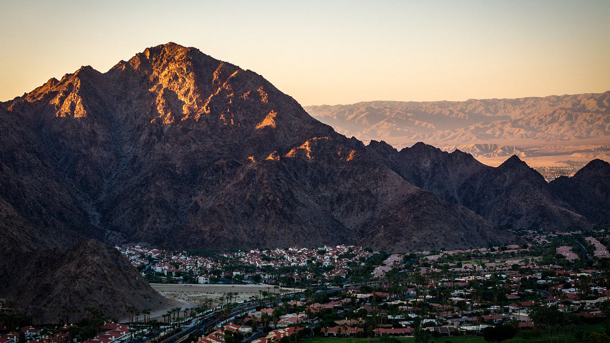 Warm light on high Santa Rosa Mountain slopes above shaded homes, palms and lower terrain in La Quinta. Photograph by Mark Miller.