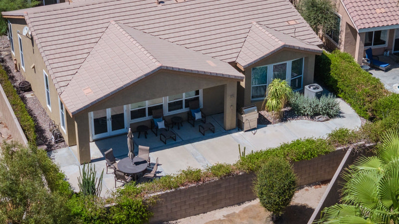 Aerial view of a Coachella Valley home with a covered patio, outdoor seating, and desert landscaping.