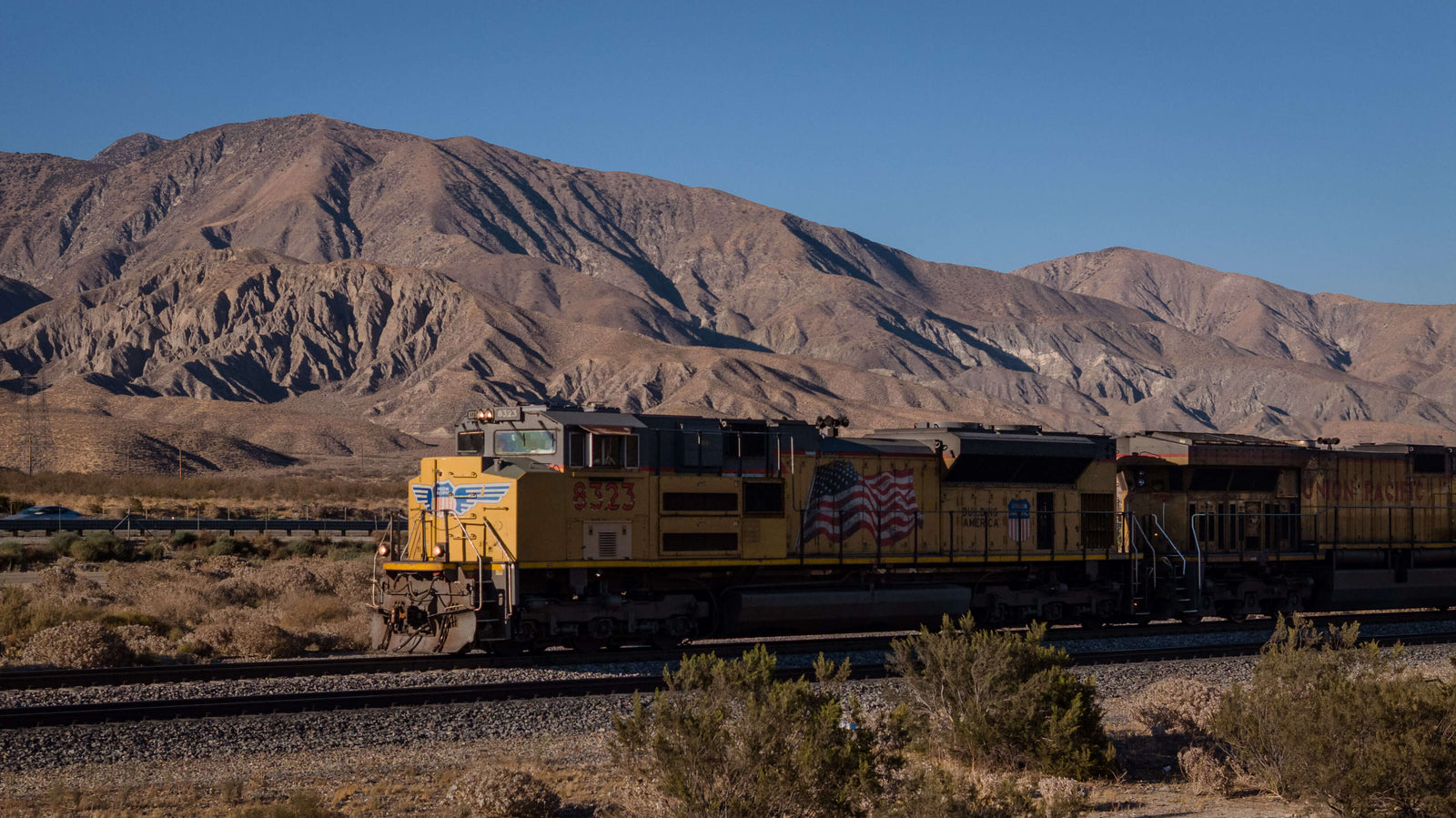 Union Pacific freight locomotive traveling through the San Gorgonio Pass with desert mountains behind it.