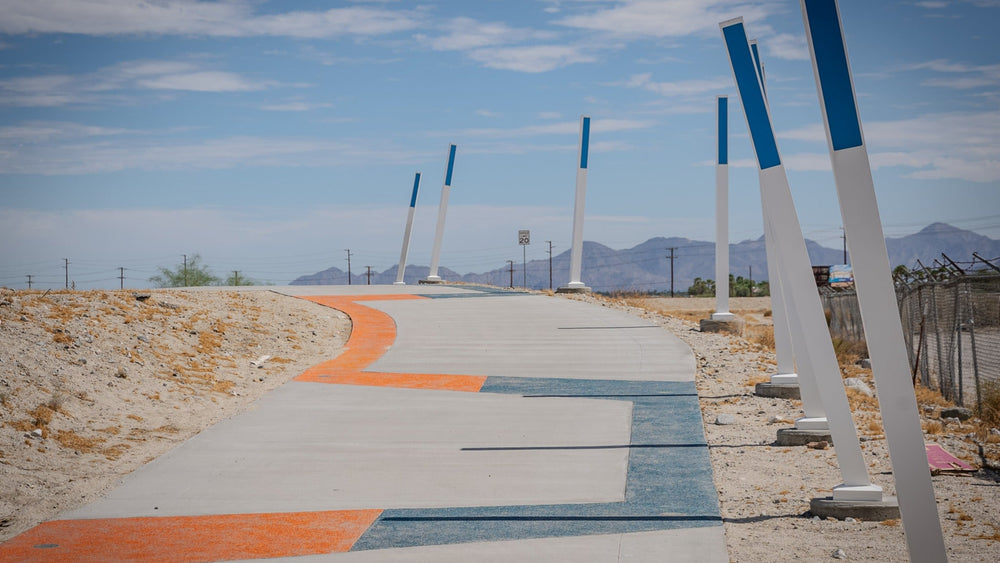 CV Link pathway in Palm Springs with orange and blue pavement markings, tilted blue-and-white posts and mountain views.