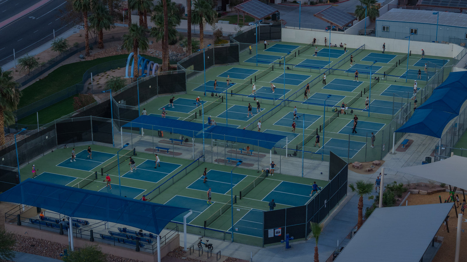 Elevated view of players using the 16 pickleball courts at Fritz Burns Park in La Quinta at sundown.