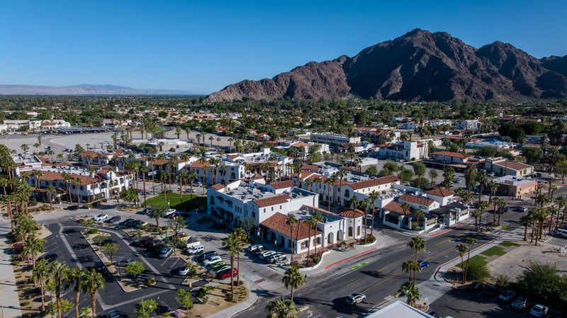 Aerial view of Old Town La Quinta and the surrounding village, with palm-lined streets and the Santa Rosa Mountains behind.