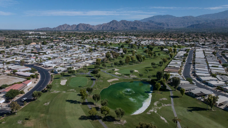 Aerial view of a Palm Desert Greens fairway, surrounding homes and desert mountains