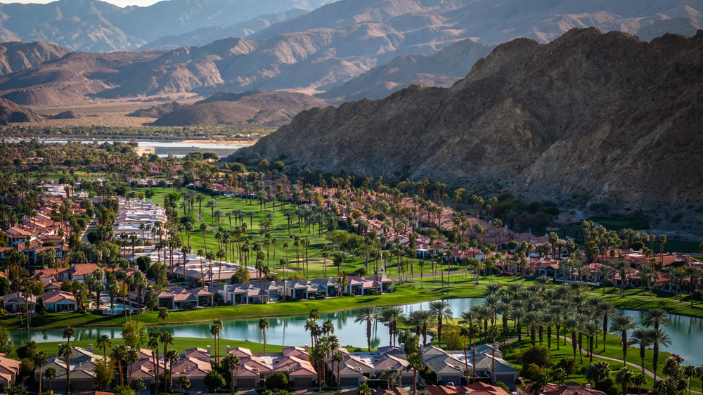 Aerial view of homes, fairways and a lake at PGA WEST’s Arnold Palmer course, with the Santa Rosa Mountains beyond.