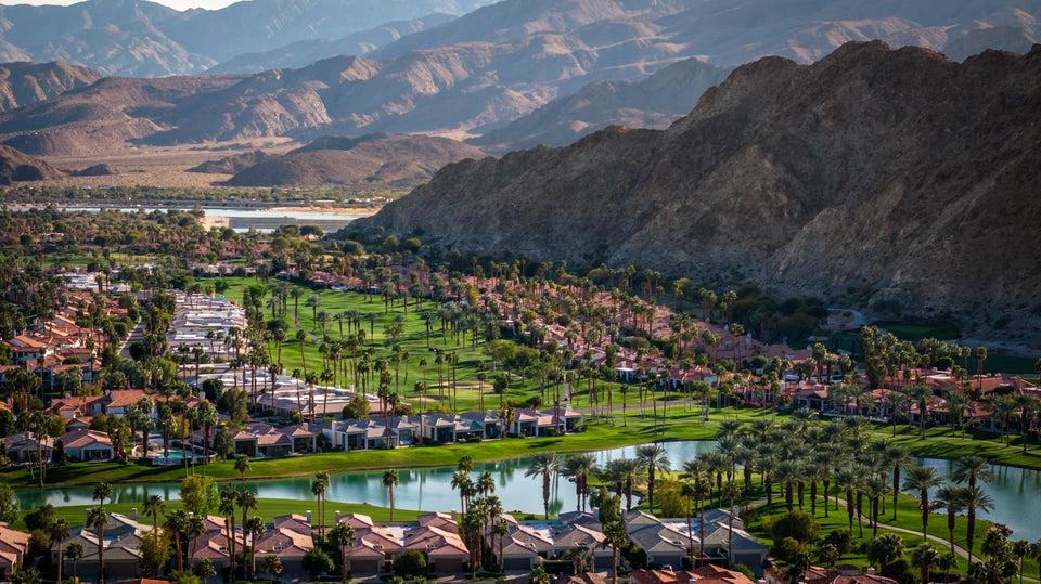 Aerial view of homes, fairways and a lake at PGA WEST’s Arnold Palmer course, with the Santa Rosa Mountains beyond.