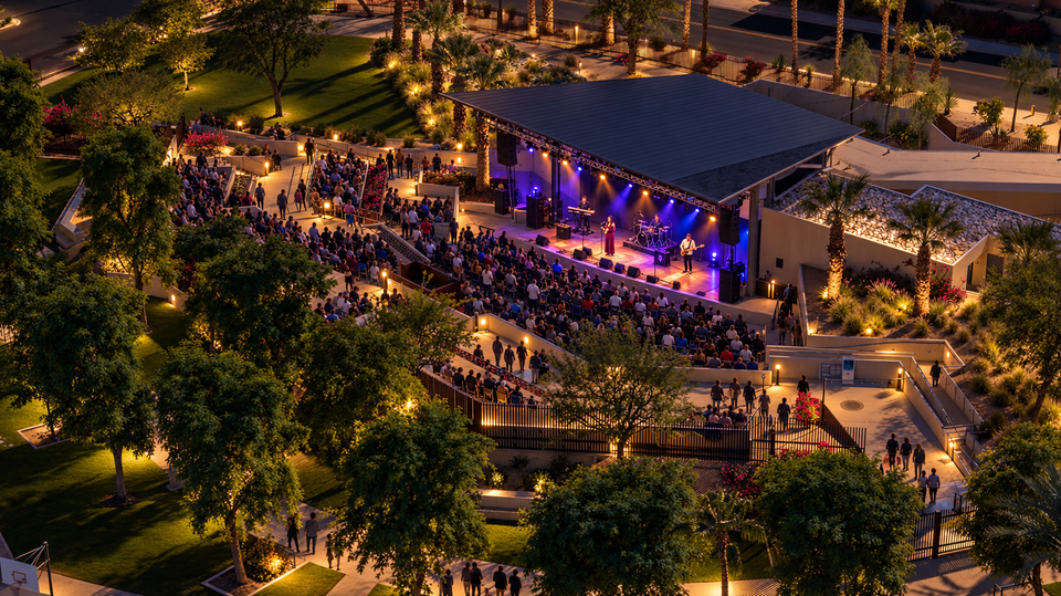AI visualization of a nighttime concert at Rancho Mirage Amphitheater, with a live band, seated audience and illuminated park.