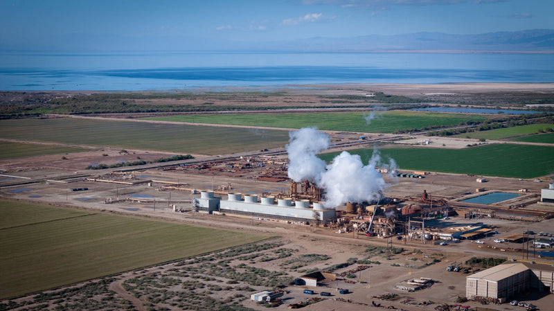 White plumes rise above a geothermal facility surrounded by fields, with the Salton Sea beyond; photograph by Mark Miller, January 8, 2026.