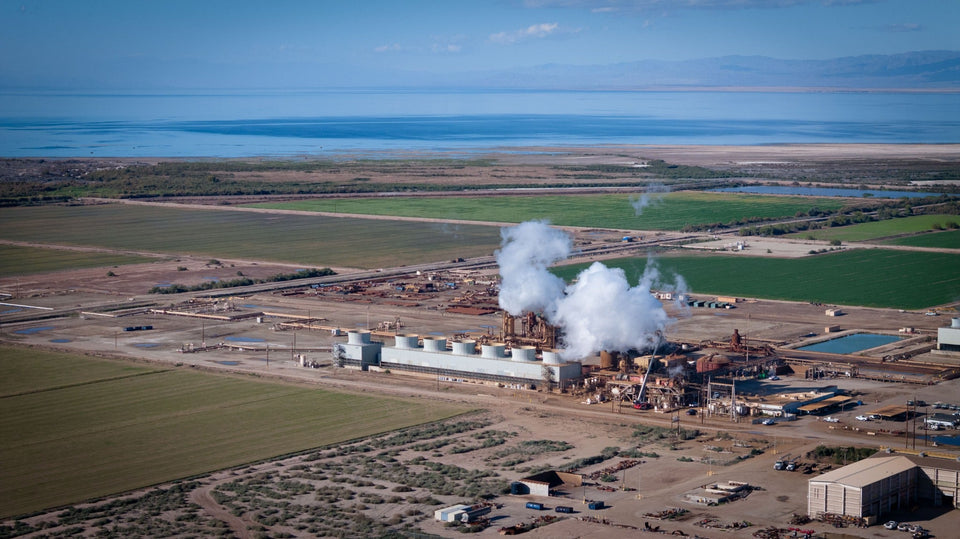 White plumes rise above a geothermal facility surrounded by fields, with the Salton Sea beyond; photograph by Mark Miller, January 8, 2026.
