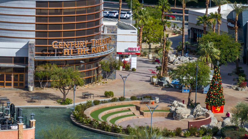 Elevated view of Century Theatres, the waterfront amphitheater, palm-lined walkways, and a Christmas tree at The River at Rancho Mirage.
