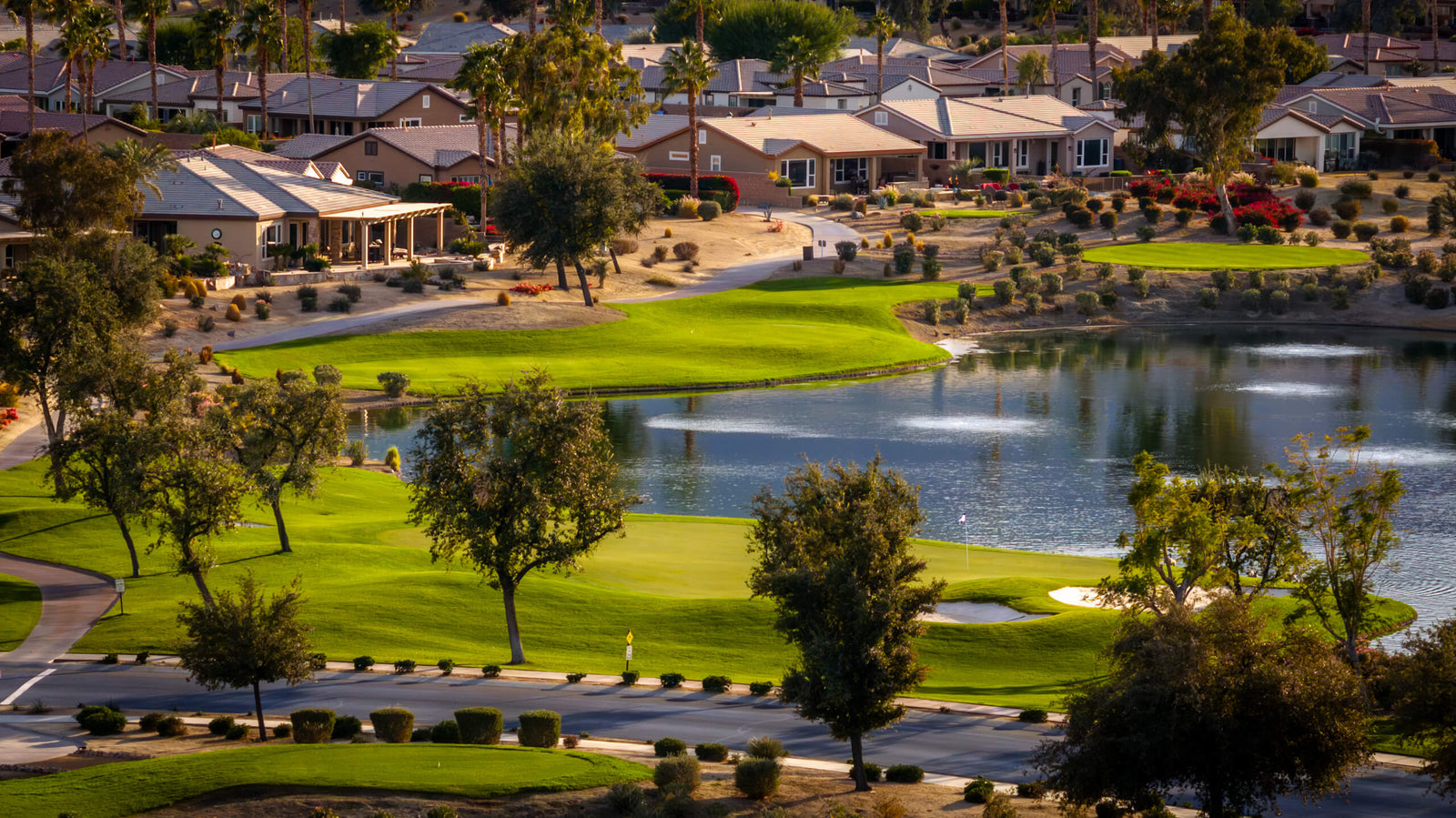 Aerial view of Trilogy at La Quinta's championship golf course with lakefront fairways and single-family homes.