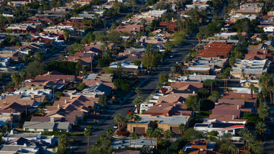 Close aerial view of La Quinta Cove homes with tile and flat roofs, palm trees and residential streets.