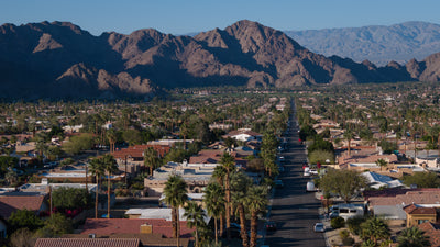 View down a palm-lined La Quinta Cove street with homes and mountains beyond, February 2026.