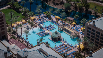 Renaissance Esmeralda pool complex with blue loungers, yellow cabanas and palms, seen from above.
