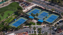 Aerial view of a tennis complex with multiple blue courts surrounded by greenery and parking lots at the Montecito Clubhouse in sun city shadow hills ca