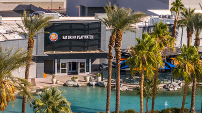 Dave & Buster’s entrance framed by palm trees and the lagoon at The River in Rancho Mirage