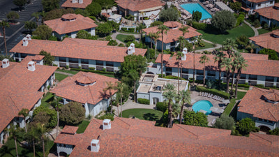 Tommy Bahama Miramonte guest buildings, palm trees, lawns and a small pool.