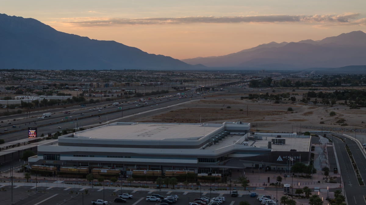 Aerial view of the entire Acrisure Arena at sunset, with mountain silhouettes on both sides of the Coachella Valley in the background.
