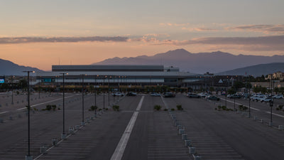 Acrisure Arena and its parking area at sundown, with a mountain ridge beneath the evening sky.