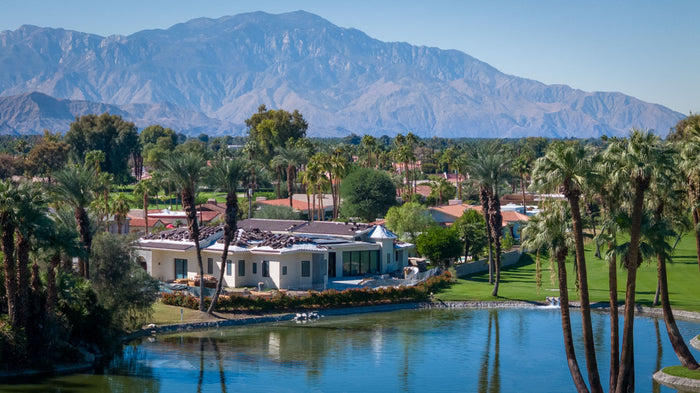 Golf course lake, palm trees and clubhouse beneath distant mountains at Bermuda Dunes Country Club, California. Photograph by Mark Miller.