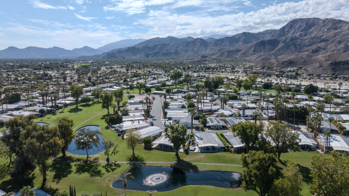 Date Palm Country Club homes, golf fairways and ponds beneath the desert mountains.