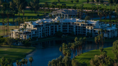 Desert Island condominium balconies overlooking the lake, with palms and golf fairways beyond.