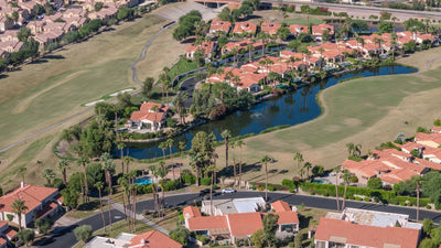 Wide aerial view of Duna La Quinta homes surrounded by golf fairways and a lake
