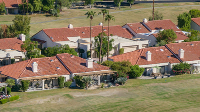 Aerial view of Duna La Quinta stucco homes with tiled roofs, patio pergolas and garages