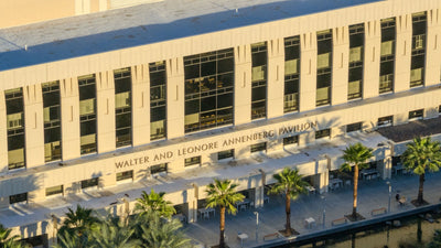 Sunlit Annenberg Pavilion facade, windows and name lettering above the landscaped terrace.
