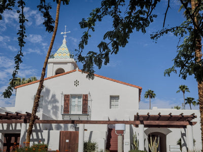 White stucco facade and wooden shutters beneath El Mirador Tower. Photograph by Mark Miller, October 20, 2026.