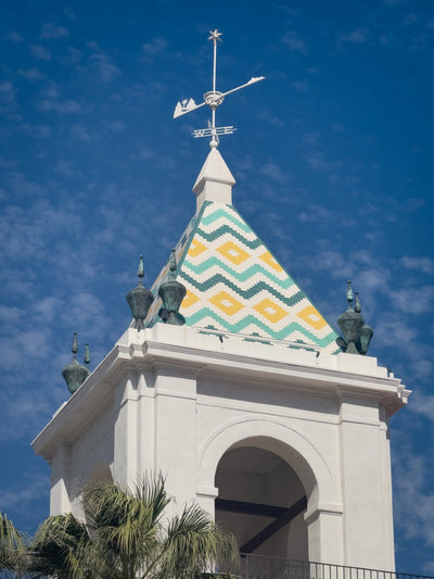 Green, yellow and white geometric roof tiles and weather vane atop El Mirador Tower. Photograph by Mark Miller, October 20, 2026.