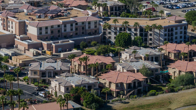 Closer elevated view of the Embassy Suites La Quinta hotel exterior with palm trees and neighboring residences in the foreground.