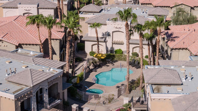 Pool and spa among neighboring residences near Embassy Suites La Quinta, surrounded by palms and tiled-roof buildings.