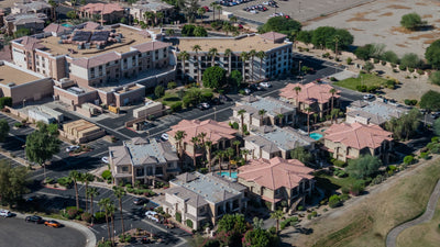 Embassy Suites La Quinta behind neighboring low-rise buildings, palm trees, and landscaped grounds.