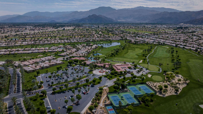 Aerial view of Heritage Palms clubhouse, golf course, courts, and mountain surroundings