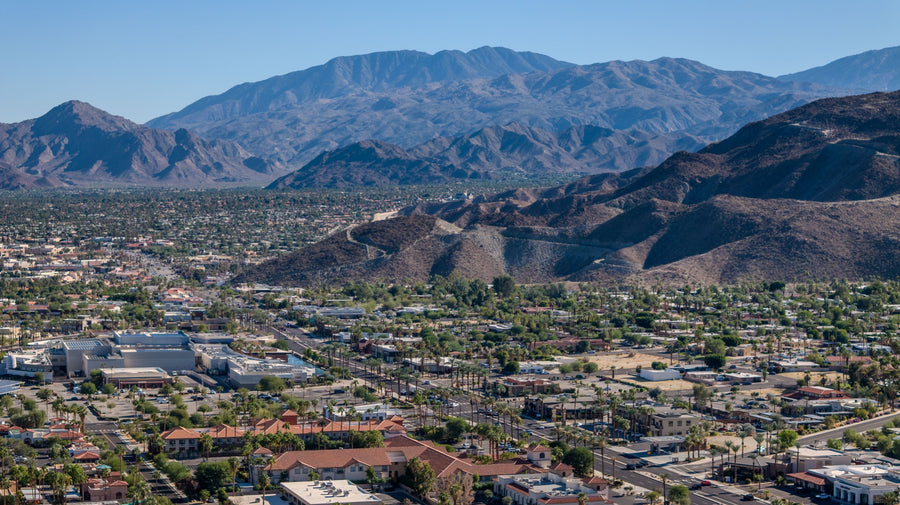 Highway 111 in Rancho Mirage, California, with palm-lined neighborhoods and the Santa Rosa Mountains in the background.