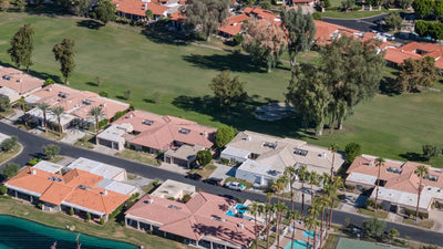 Homes lining a tree-shaded fairway at La Quinta Country Club, with a lake and courts at the edge of the aerial view.