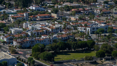 Elevated view of Old Town La Quinta with white stucco buildings, red tile roofs, palm trees, and the surrounding neighborhood.