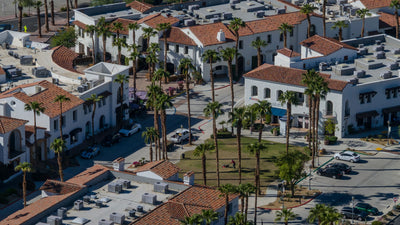 Palm-lined streets, shops, and a central lawn in Old Town La Quinta viewed from above.