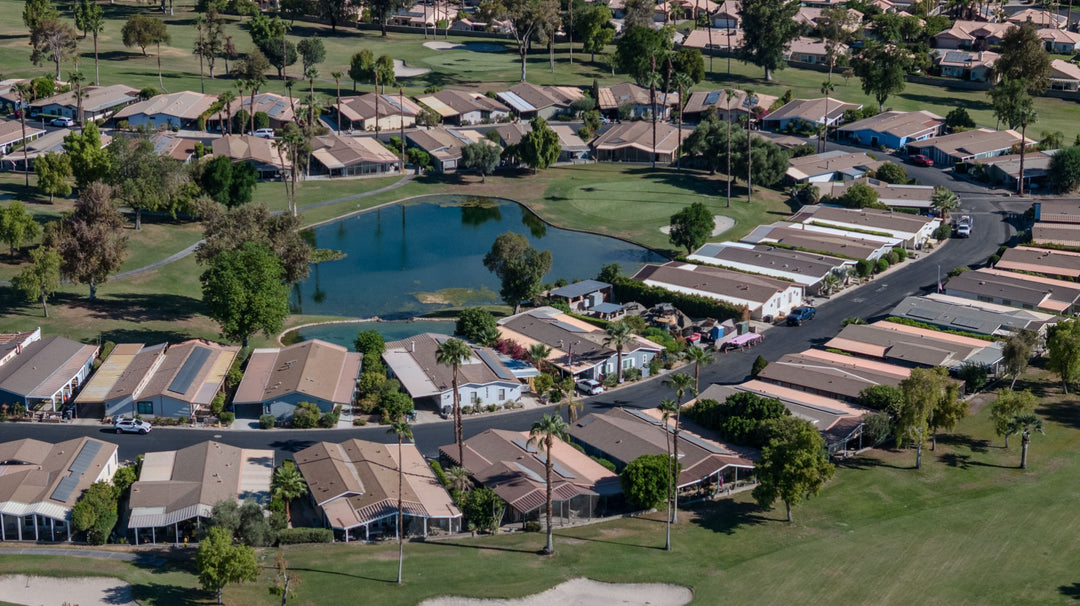 Homes around a golf-course pond with fairways and bunkers at Palm Desert Greens