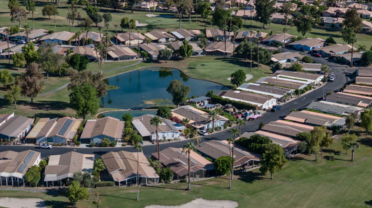 Homes around a golf-course pond with fairways and bunkers at Palm Desert Greens
