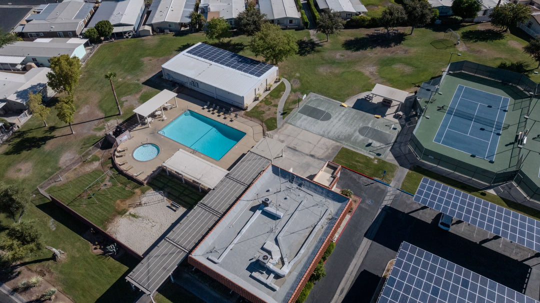 Aerial view of a pool, spa, recreation buildings and neighboring courts