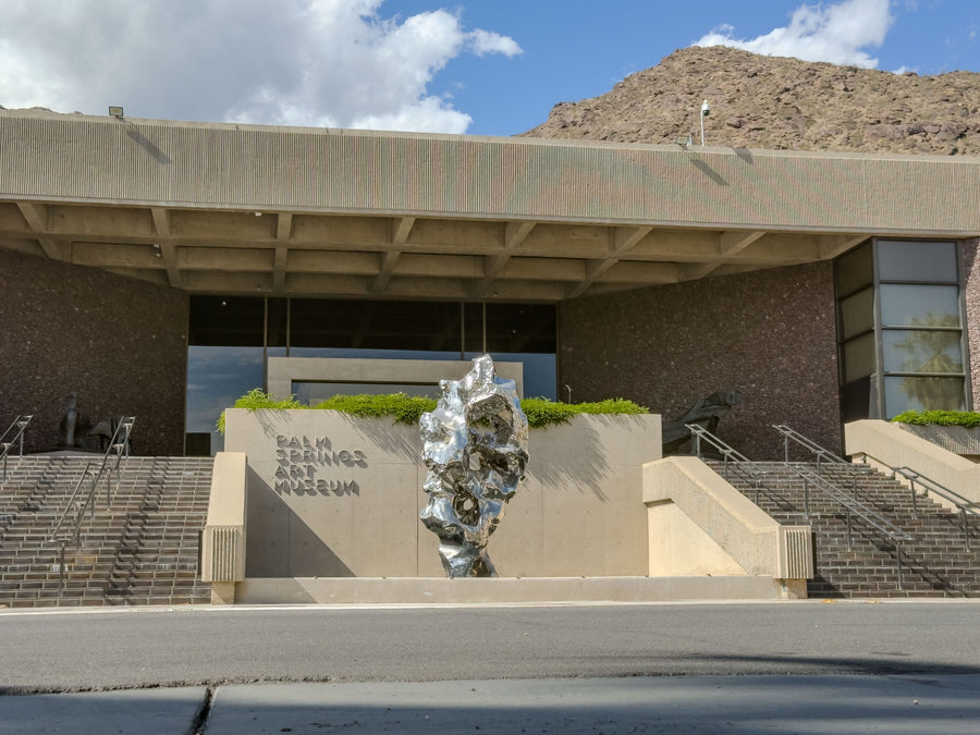 Palm Springs Art Museum entrance, broad stairs and reflective sculpture beneath the mountain slope. Photograph by Mark Miller, October 20, 2026.