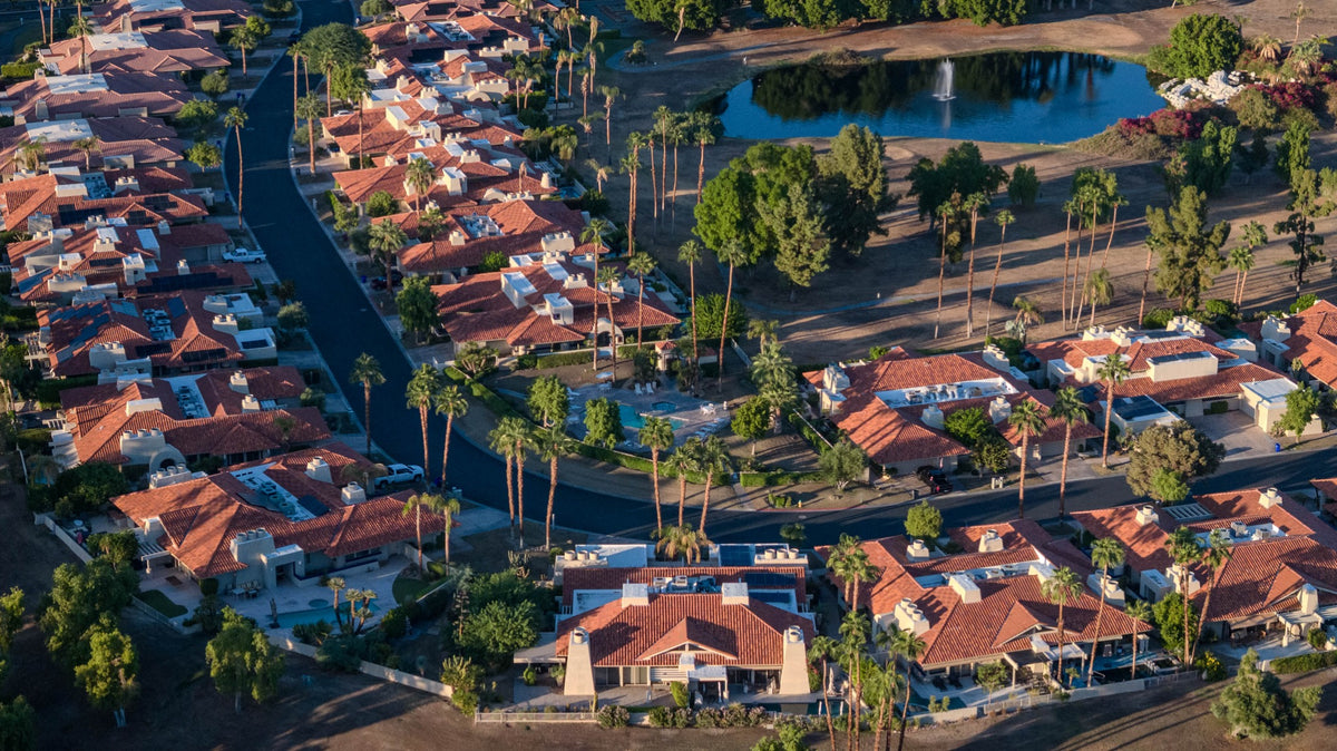 Rancho Mirage Country Club homes, palms and a neighborhood pool beside a lake with a fountain.