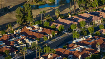 Red-tile roofs and solar panels on Rancho Mirage Country Club homes beside a lake.