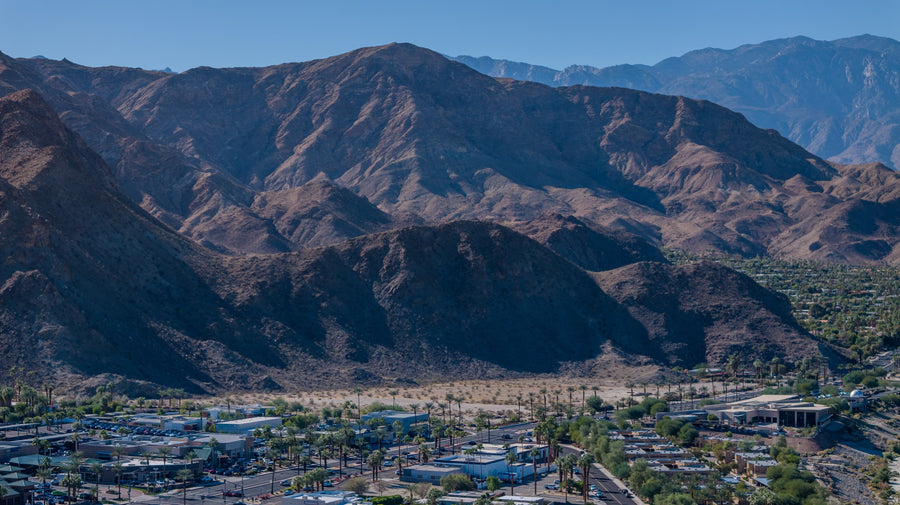Rugged Santa Rosa Mountains rising above palm-lined streets and buildings in Rancho Mirage, California.
