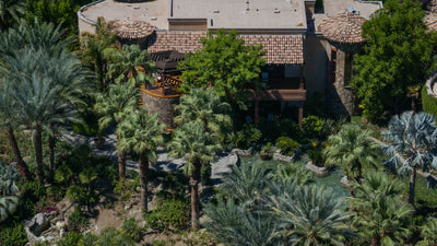 Resort building with a tiled roof and shaded terraces among dense palms at Sensei Porcupine Creek.