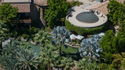 Round-roof pavilion and resort buildings set among palms and gardens at Sensei Porcupine Creek.